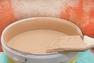 A can of paint and a brush against an old textured wall. A room renovation concept