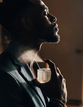 Side profile of stylish Black man spraying luxury cologne on his neck, grooming and fragrance commercial concept