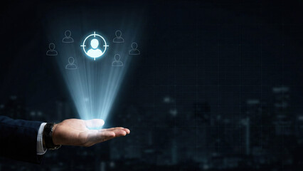 Hand holding glowing user icon with target symbol, representing customer focus and digital connection in dark city background