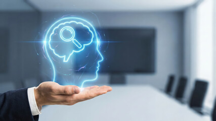 Hand holding glowing human head with brain and magnifying glass symbol, representing mental analysis and research in office setting