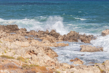 Powerful surf hitting rocks emerald blue sea white foam and clear sky