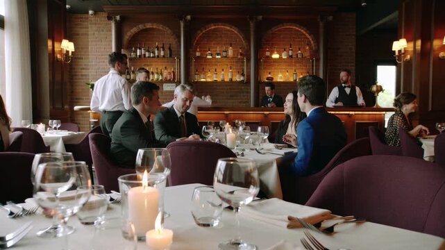 Fine dining scene with guests conversing at candlelit tables while attentive waiters serve plates and drinks beside a warm, elegant bar creating a sophisticated evening ambience