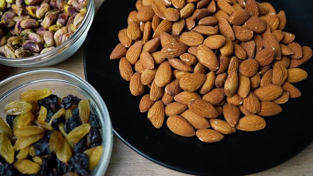 Variety of nuts and dried fruits in bowls on a wooden surface
