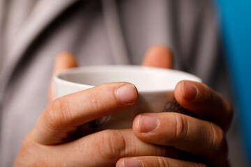 A close-up of a person holding a white mug, embodying warmth, comfort, and relaxation. Perfect for cafe or mor © vegefox.com