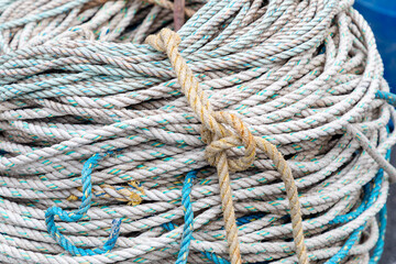 Coiled nautical rope bundles with multicolour fibres and weathered tan cord ties along dock edge
