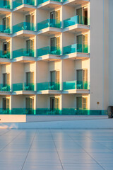 Fototapeta premium Sunlit turquoise glass balcony facades of a modern hotel resort with repeating pattern