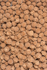 A vertical close-up shot of a dense, textured background composed entirely of small, round, brown coated tapioca pearls