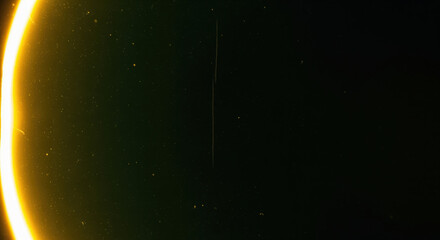 Eclipse rim light leak texture for cinematic title cards and analog film transitions featuring a bright curved edge with floating dust and a faint vertical scratch for editors and trailers