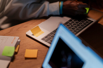 A person's hands are visible as they work on a laptop, with a sticky note reminding them of a meeting at 9:00 AM.
