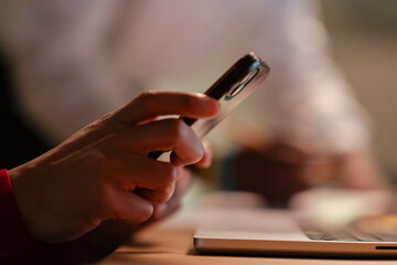 A person's hands are shown holding a smartphone, with a laptop in the foreground, suggesting a moment of digital connection or work.