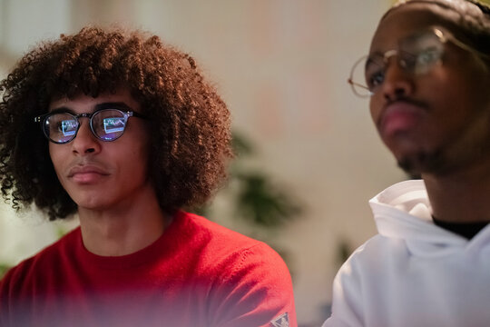 Two young men wearing glasses look intently at a screen displaying financial charts, suggesting a focus on data analysis or trading.