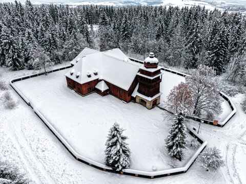 Wooden articular church in Sv&auml;t&yacute; Kr&iacute;ž Slovakia surrounded by snowy forest aerial drone view
