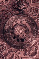 Copper antique pocket fob watch with gears and cogs in the background. Vintage industrial steampunk fashion accessories.
