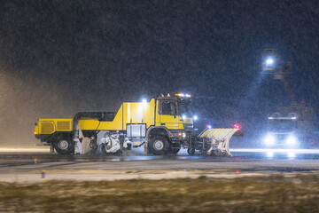 Special snow plow truck on the move along airport runway during heavy snowfall. Scene shows winter...