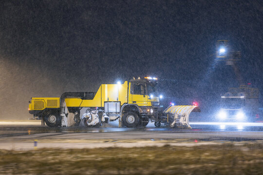 Fototapeta Special snow plow truck on the move along airport runway during heavy snowfall. Scene shows winter maintenance in harsh weather at night.