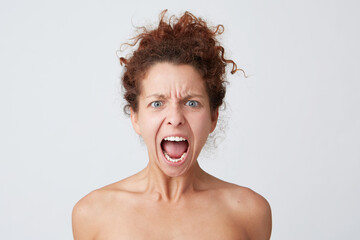 Close up shot of angry mad young woman with curly hair and healthy skin opened mouth and shouting loudly isolated over white background Feels stressed after hard day