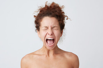 Horizontal shot of crazy hysterical young woman with curly hair and soft healthy skin close eyes and screaming isolated over white background Looks stressed and feels angry