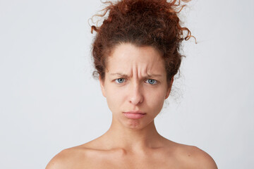 Horizontal shot of pensive confused young woman with curly hair and healthy skin standing half naked and looks worried isolated over white background Feels stressed and abused after shower