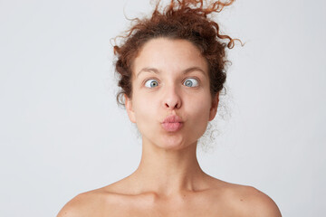Horizontal shot of amazing crazy young woman with curly hair and perfect skin making funny face and joking isolated over white background Joyful girl having fun after taking shower