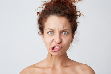 Close up shot of comical amusing young woman with curly hair and healthy skin making unhappy funny face and having fun after taking shower isolated over white background