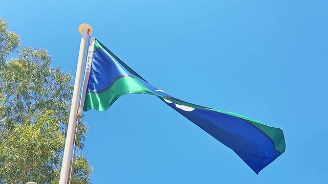 Torres Strait Islander flag flying against a blue sky