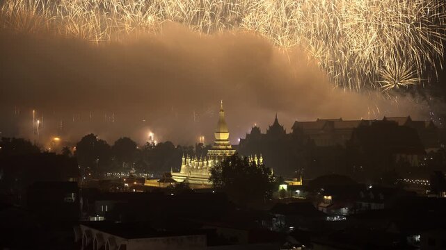 Multi-Color Firework Bursting Above Vientiane's Golden Pha That Luang Stupa at Night during National Celebration