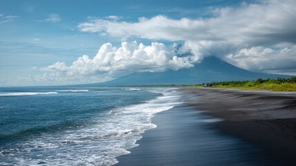 Scenic black sand beach with ocean waves meeting the shore and a majestic volcano under a cloudy sky. Tropical nature for travel.
