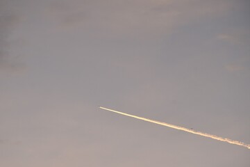 vapor trails from jet plane on sunset sky in evening