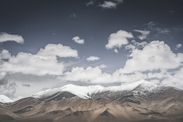 Landscape in the Pamir Mountains of Tajikistan with snow, glaciers, and cliffs, a panorama of mountains in cloudy weather for the background, nature in the Tien Shan highlands, landscape background