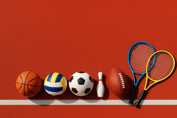 Various sports equipment including balls and rackets neatly arranged on a red textured surface with white line, symbolizing athletic diversity concept. Ai generative