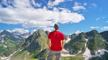 Man in red t-shirt stand and look on the snow mountain.