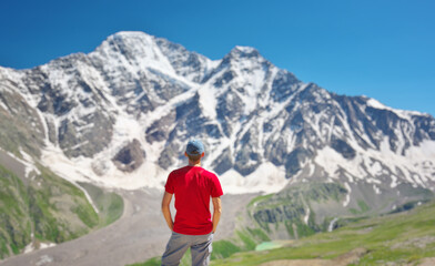 Man in red t-shirt stand and look on the snow mountain.