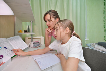 Mother helping daughter to complete school tasks.