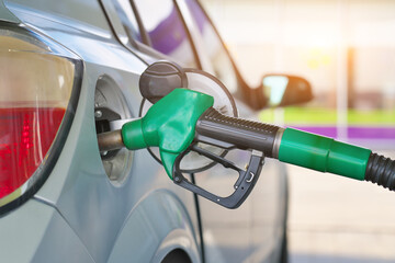 Refueling gun inserted into silver car s fuel tank with diesel or petrol.