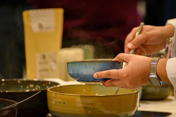 Hands serving hot soup in blue bowl The Concept of Hospitality