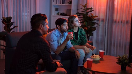 Top view of caucasian father and relaxed mother watching movie while eating snack with friend. Happy family with colleague looking at television while dad hold snack bowl at living room. Convocation.