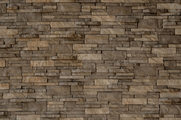 Brown and grey natural stone wall texture with stacked rectangular slate tiles, perfect for architectural backgrounds.