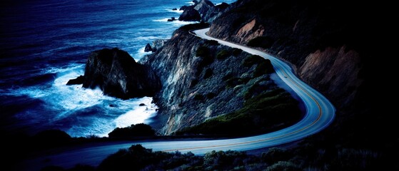 Coastal road winding along rugged cliffs with ocean waves at night