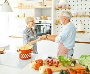 Portrait of happy senior couple prepering meal and dancing in kitchen