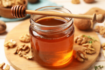 Sweet honey with walnuts and dipper on table, closeup