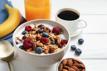 Healthy breakfast. Oatmeal with nuts, berries and milk on white wooden table, closeup