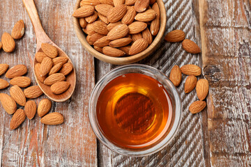 Honey in jar and almonds on wooden table, flat lay