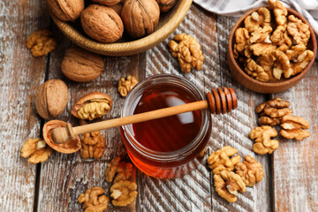 Fototapeta premium Honey in jar, walnuts and dipper on wooden table, above view