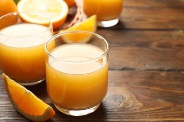 Fresh orange juice and fruits on wooden table, closeup. Space for text