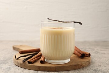 Delicious protein shake in glass, cinnamon and vanilla pods on grey table, closeup