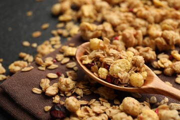 Tasty granola with dried fruits and spoon on table, closeup