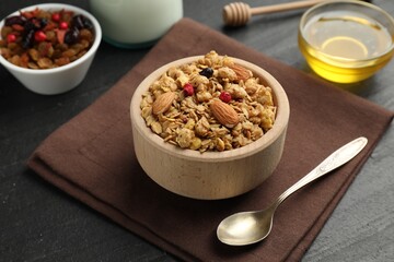 Tasty granola with dried fruits, nuts, honey and milk on black table, closeup