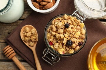 Tasty granola with dried fruits, nuts, milk and honey on wooden table, flat lay