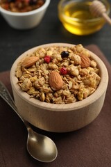 Tasty granola with dried fruits, nuts and honey on black table, closeup