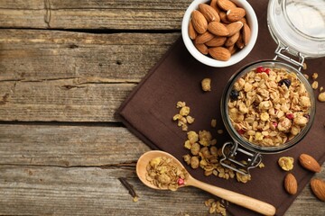 Tasty granola with dried fruits, nuts, milk and honey on wooden table, flat lay. Space for text